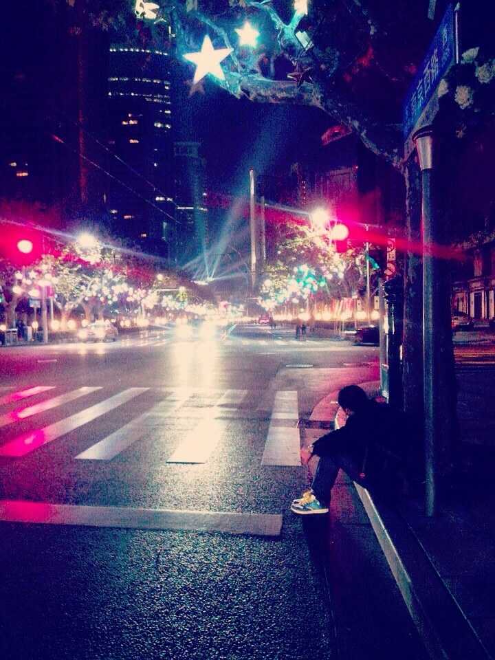 拍摄于一个元旦的凌晨 年轻的打工仔加班后累到坐在路边休息 城市的灯