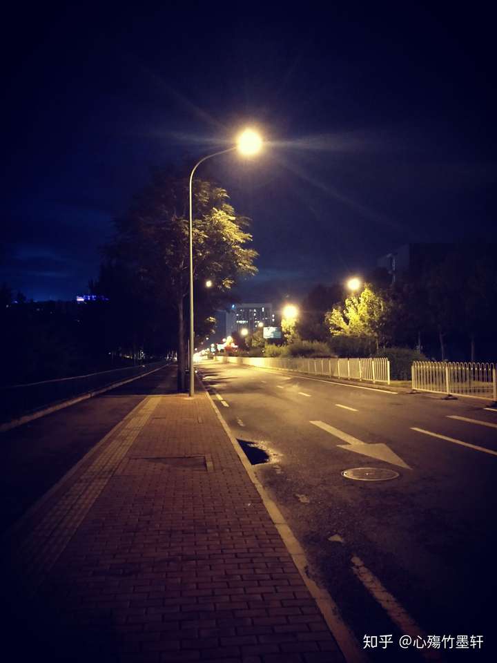 一个人走在一条很长很长的马路上,夜晚的马路开着路灯,虽然是暖色调的