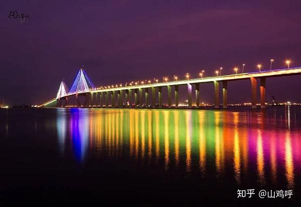 夜幕降临,湛江海湾大桥散发出绚丽的灯光,与水中的倒影交相辉映,像两