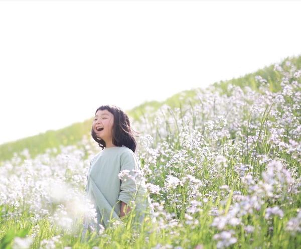 花丛中,山坡上,孩子迎风而立,微风轻抚头发,灿烂的笑容,照片里满满的