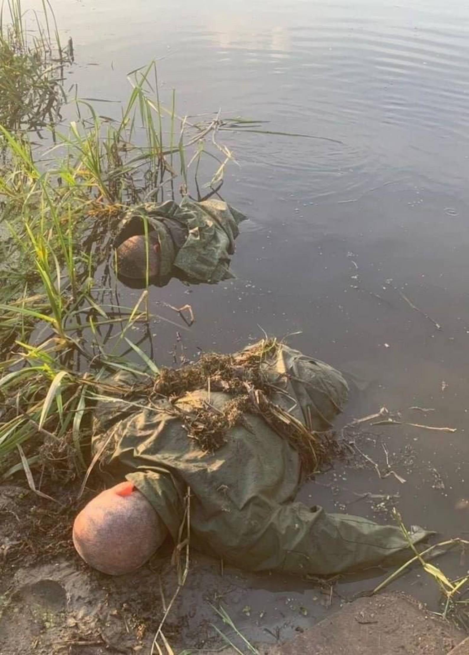 照片显示俄军士兵遗体卡在河岸地区的草丛