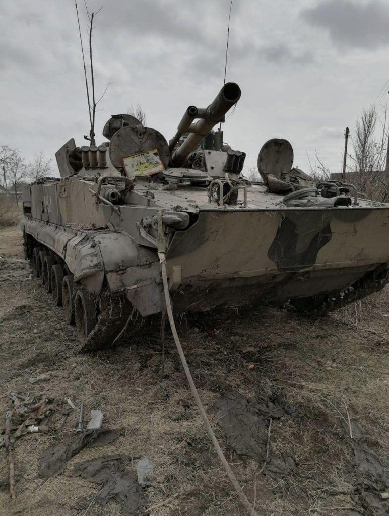 在未知地點,圖片顯示一輛烏軍的悍馬救護車被摧毀,一名烏軍士兵隨車