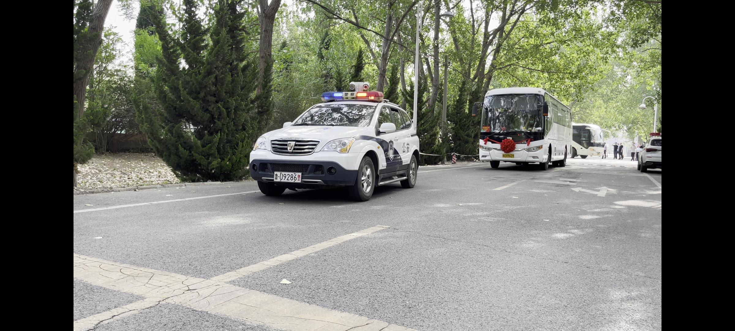 在警車護送下,4輛滿載城陽區第八中學中考學子的送考巴士安全抵達城陽