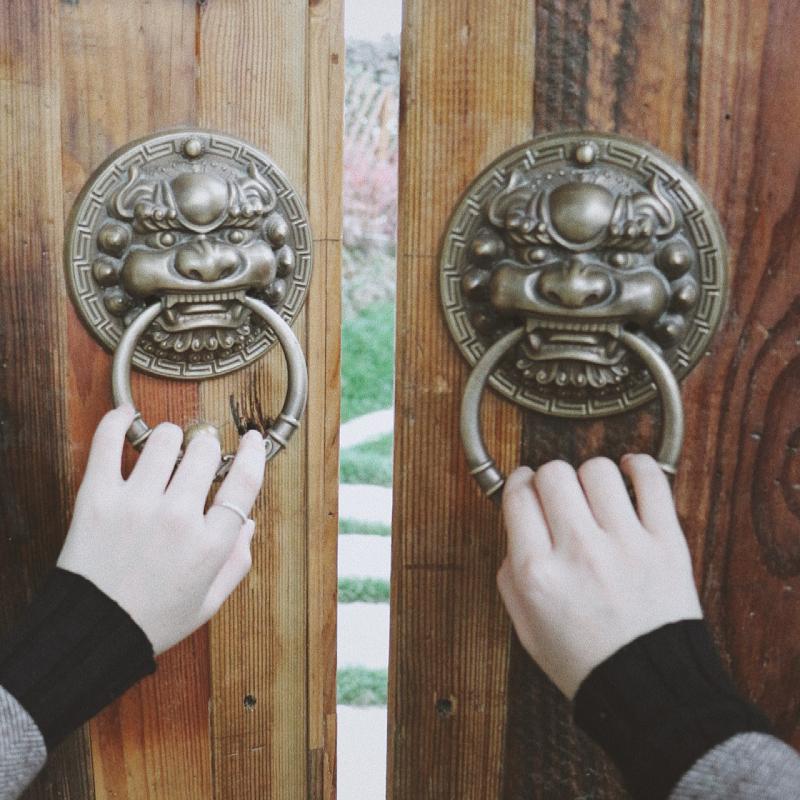 的镲钹状金属构件反扣于门板之上,中间高凸位置连接一金属环或金属坠